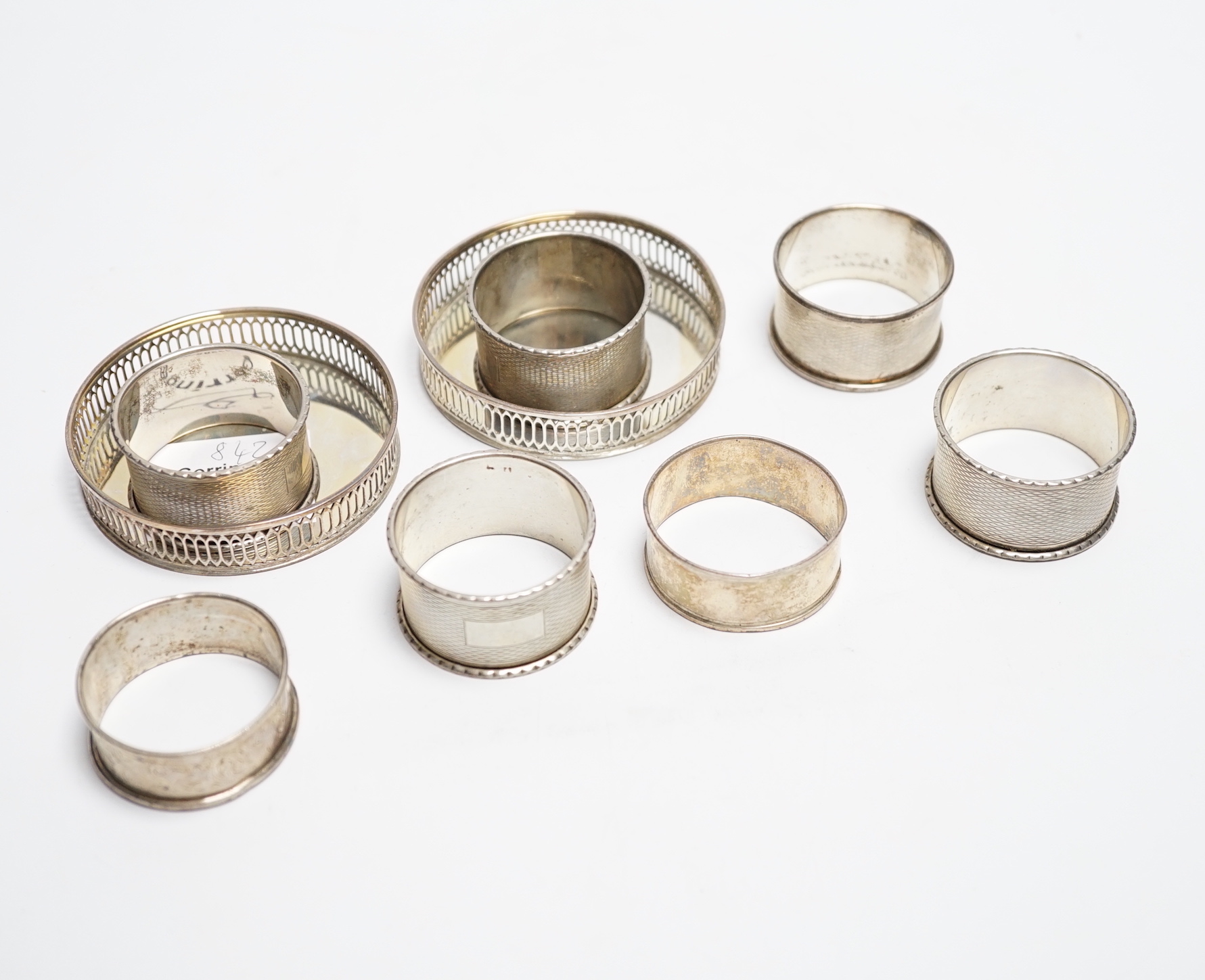 Two modern silver wine glass coasters, Walter Edward King, London, 1972, 77mm and seven silver napkin rings including a set of four.